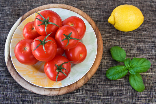 Tomaten auf einem Teller mit Basilikum und Zitrone