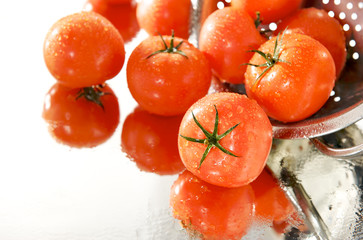 dojrzale czerwone pomidory w sitku, na białym tle, mokre, lustro - obrazy, fototapety, plakaty
