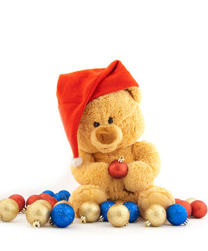 Toy bear in a Christmas cap and with Christmas-tree decorations