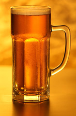 Mug of lager beer with bubbles on yellow