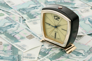 Old alarm clock against the Russian money