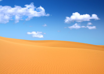 sand dunes and cumulus clouds over them, focus set in foreground
