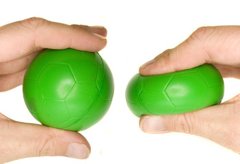 a man's hand squeezing a green stress ball.