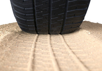 Black tyre and track on sand