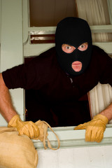 A burglar robbing a house wearing a balaclava.