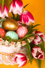 Easter colored eggs and pink tulips in a porcelain basket