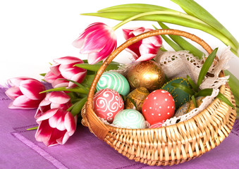 Easter colored eggs and pink tulips in in  basket