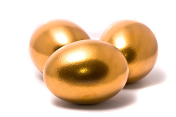 Three golden eggs on studio white background