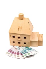 Wooden small house on a roll of money