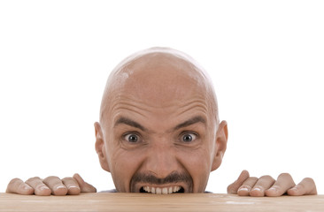 Mann mit Glatze beißt in Tischkante