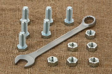 Bolts and nuts and nut wrench on a hessian