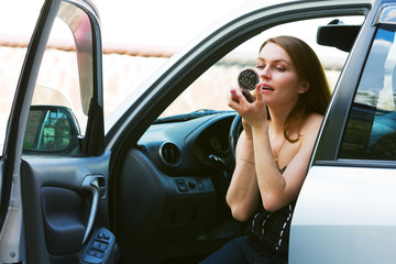 Young woman having make-up  in a car.