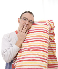 joven en pijama bostezando con almohada