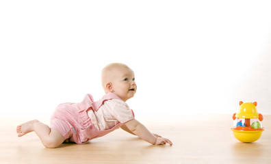 baby girl crawling towards a toy on the floor