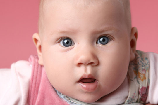 Little cute surprised child. Close-up portrait on pink backgroun