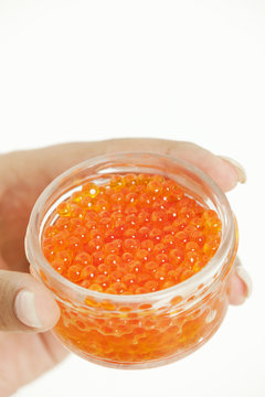 woman's hand holding bowl with red caviar