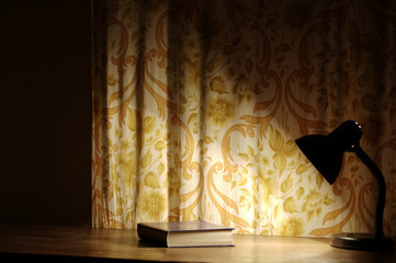 lamp that shines on the book lying on the table