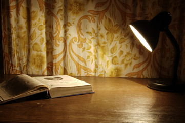 lamp that shines on the book lying on the table