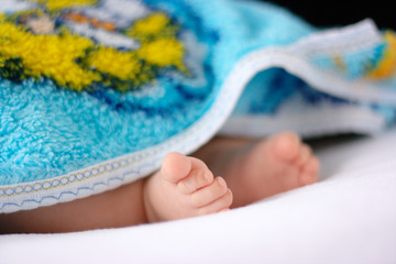 Beautiful uncovered toddler's feet on white bedsheet