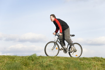 Fototapeta na wymiar A happy laughing man cycling uphill