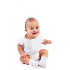 Happy smiling infant baby dressed in white sitting isolated