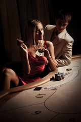 Young man & woman playing poker in casino