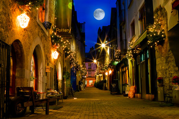 old street decorated with lights and full moon