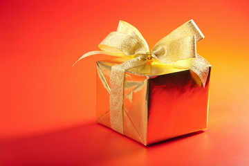 golden gift box with bow over red background