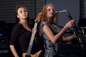two young female play on guitar and saxophone