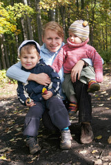 Happy family of mother and two sons in autumn forest