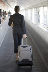 Hübsche Frau am Flughafen mit Koffer lächelnd von hinten