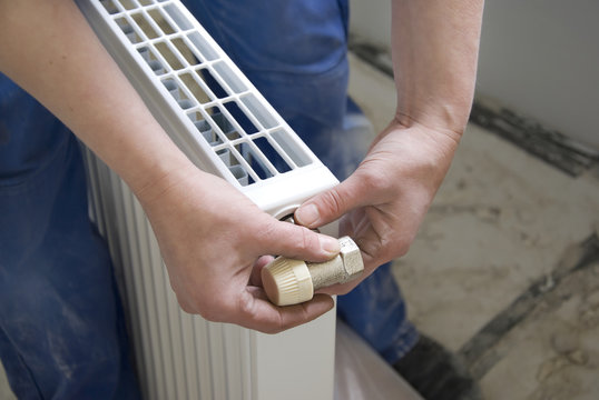 hands of a plumber installing a connection at a radiator