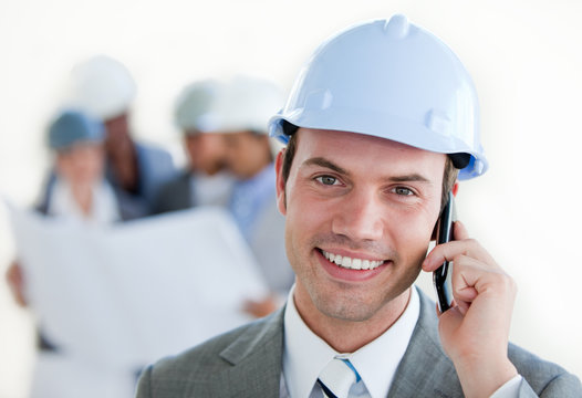 Smiling arhitect with a hardhat on phone