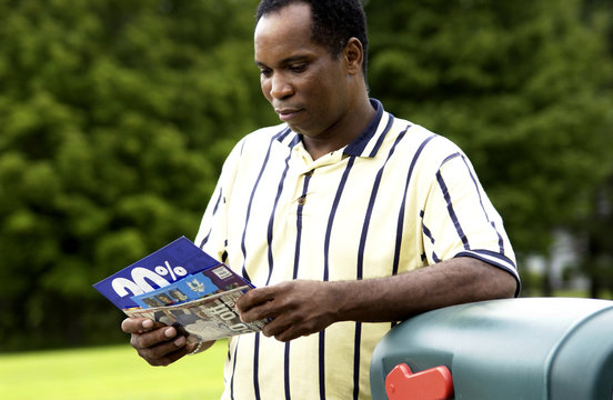 African American man getting mail from mailbox
