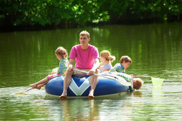 Children and adults float on an inflatable boat in a sunny day