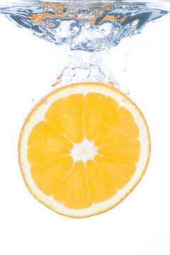 An orange slice falling into clear water