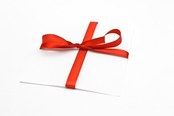 Blank gift tag tied with a bow of red satin ribbon.