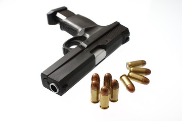 A handgun with an extended clip next to bullets
