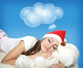 Sleeping young woman with teddy bear in santa hat