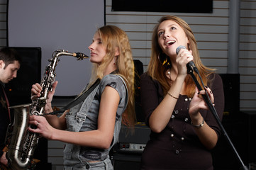 two young females sign the song and play on saxophone