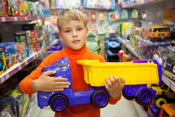 The boy in shop with toy truck in hands