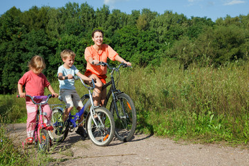 Obraz premium Mother with son and daughter ride bikes outside the city