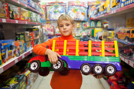 The boy in shop with the big model of the truck in hands