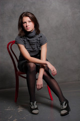 Fototapeta premium Portrait of the young girl sitting on a chair