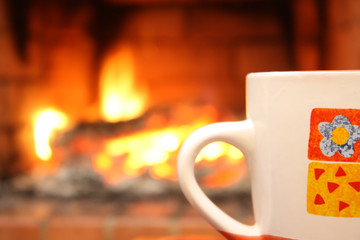 Cup, flame fnd fireplace in background