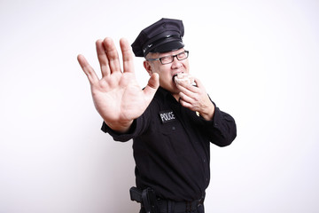 Police officer gesturing to stop while eating donut