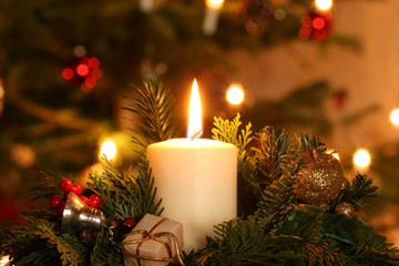 Adventskerze vor geschmücktem Weihnachtsbaum