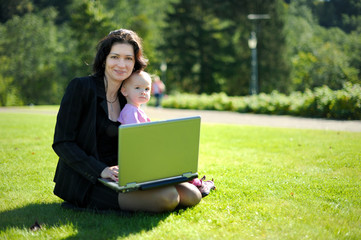 Young lady with a baby and a notebook in a park