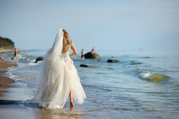 Fototapeta na wymiar Bride walking along sea coast