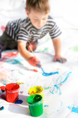 Naklejka premium young boy painting, focus on cans